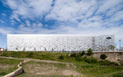 Sommarhälsning från en P-husfasad med grönska, ljusspel och havsvågor i plåt